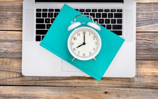 Ordenador portátil y un reloj simulando un software de control horario para el registro digital de la jornada laboral de los empleados.