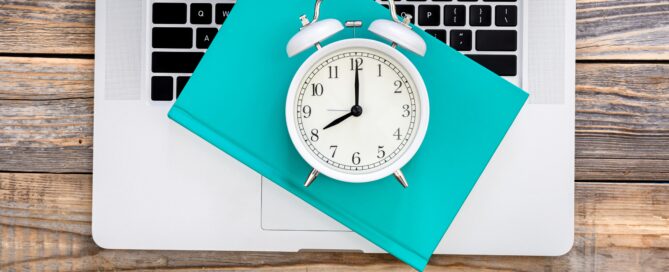 Ordenador portátil y un reloj simulando un software de control horario para el registro digital de la jornada laboral de los empleados.